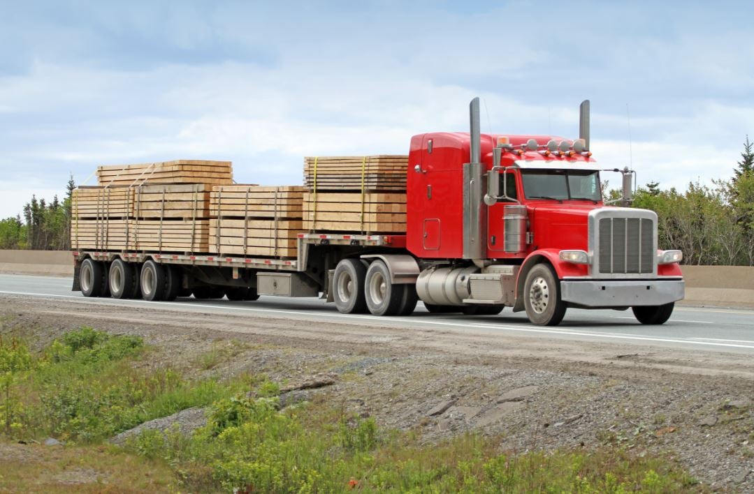Step deck style flatbed truck carrying lumber
